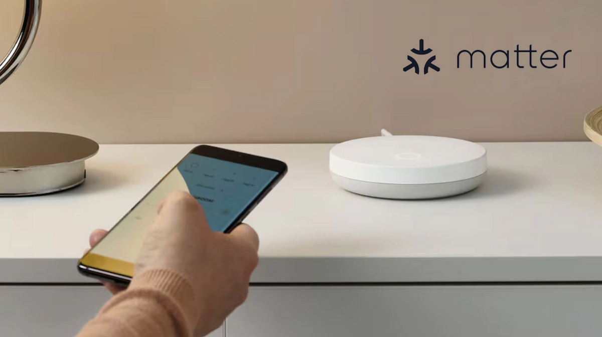 Weißer IKEA DIRIGERA Hub auf einer Kommode, davor eine Hand mit Smartphone, oben rechts das Matter-Logo