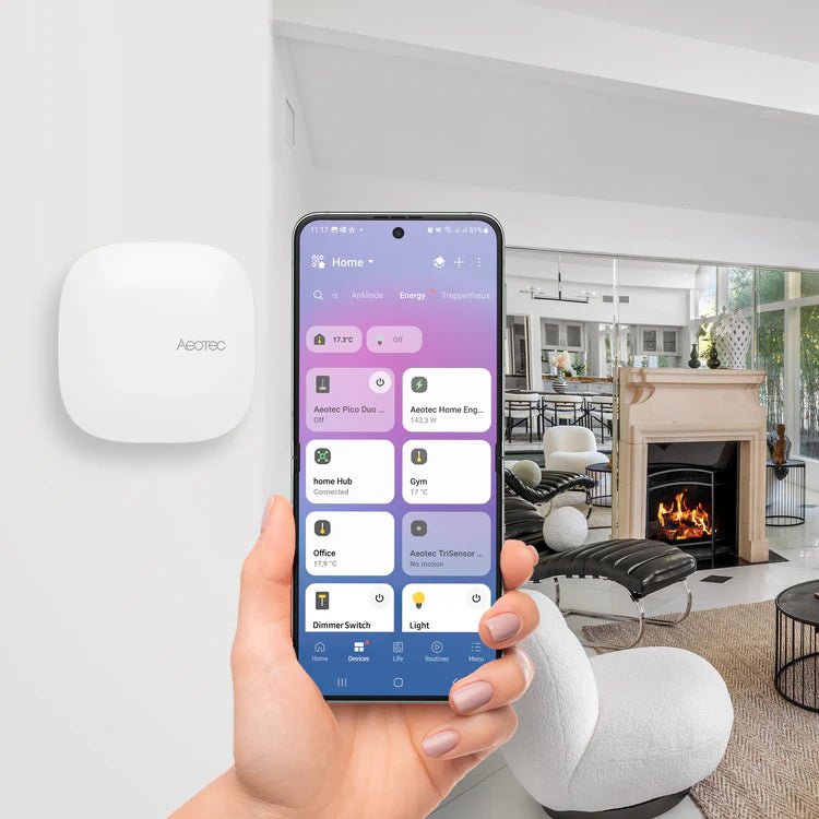 Der Hub an der Wand montiert, daneben ein Smartphone mit der App