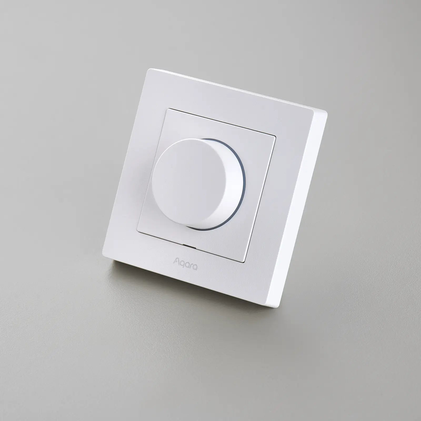 Weißer Aqara Dimmer H2 leicht gekippt vor hellgrauem Grund, mit Aqara-Schriftzug unter dem Knopf