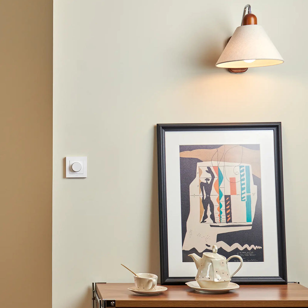 Gedimmte Wandleuchte über einer Kommode, der Aqara Dimmer H2 sitzt links an der Wand