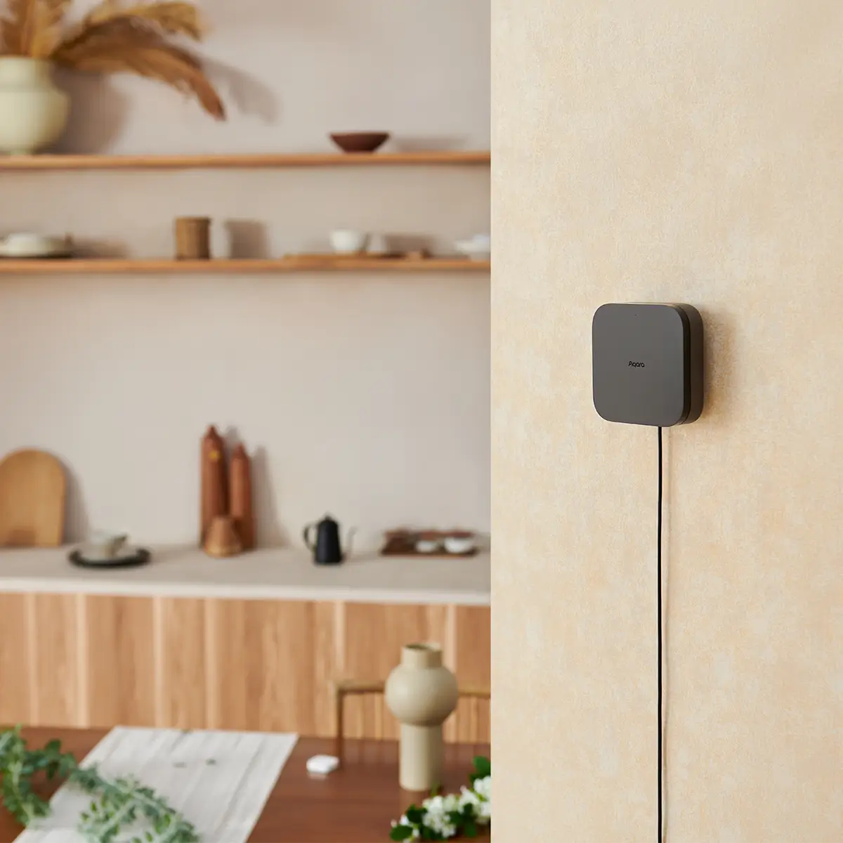 Aqara Hub M3 flach an einer beigen Wandkante montiert, das Kabel läuft sichtbar nach unten