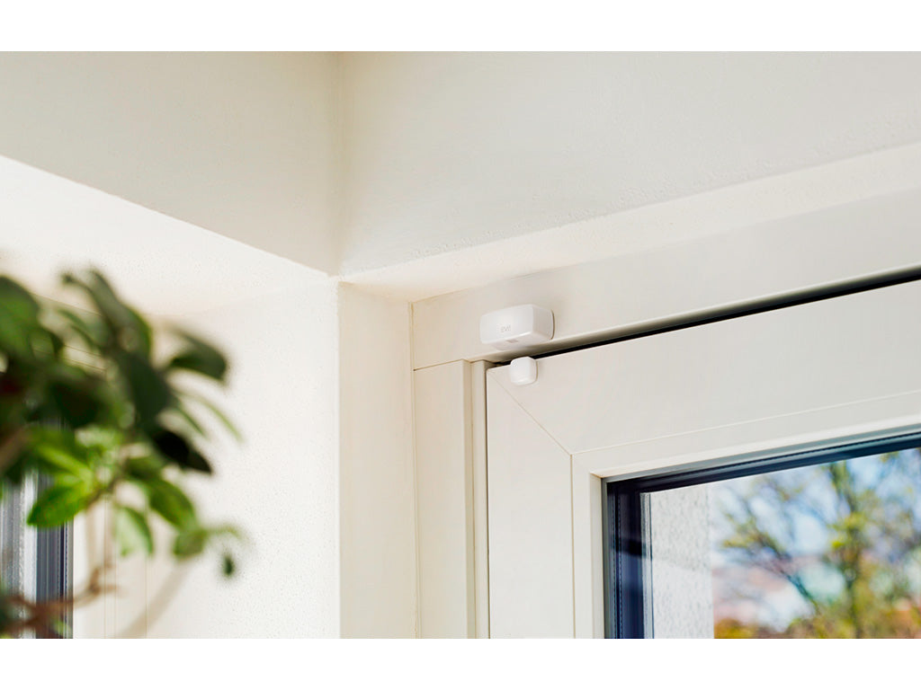 Eve Door & Window oben am weißen Fensterrahmen montiert, Zimmerpflanze im Vordergrund