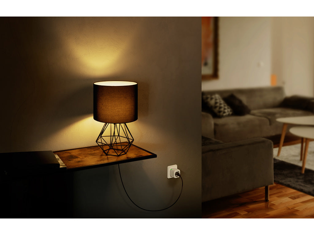 Leuchtende Tischlampe auf einem Wandbord, Eve Energy in der Steckdose darunter