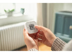 Hände halten den Eve Thermo Control, ein Finger bedient die Touch-Taste neben dem Display