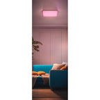 Hama Smarte LED-Deckenleuchte leuchtet pink an der Decke über einem blauen Sofa
