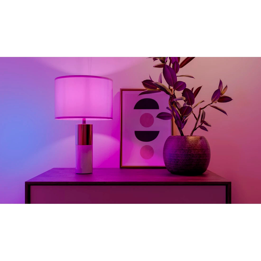 Tischleuchte mit Hama Smarter Lampe E14 taucht Sideboard, Bild und Pflanze in pink-violettes Licht