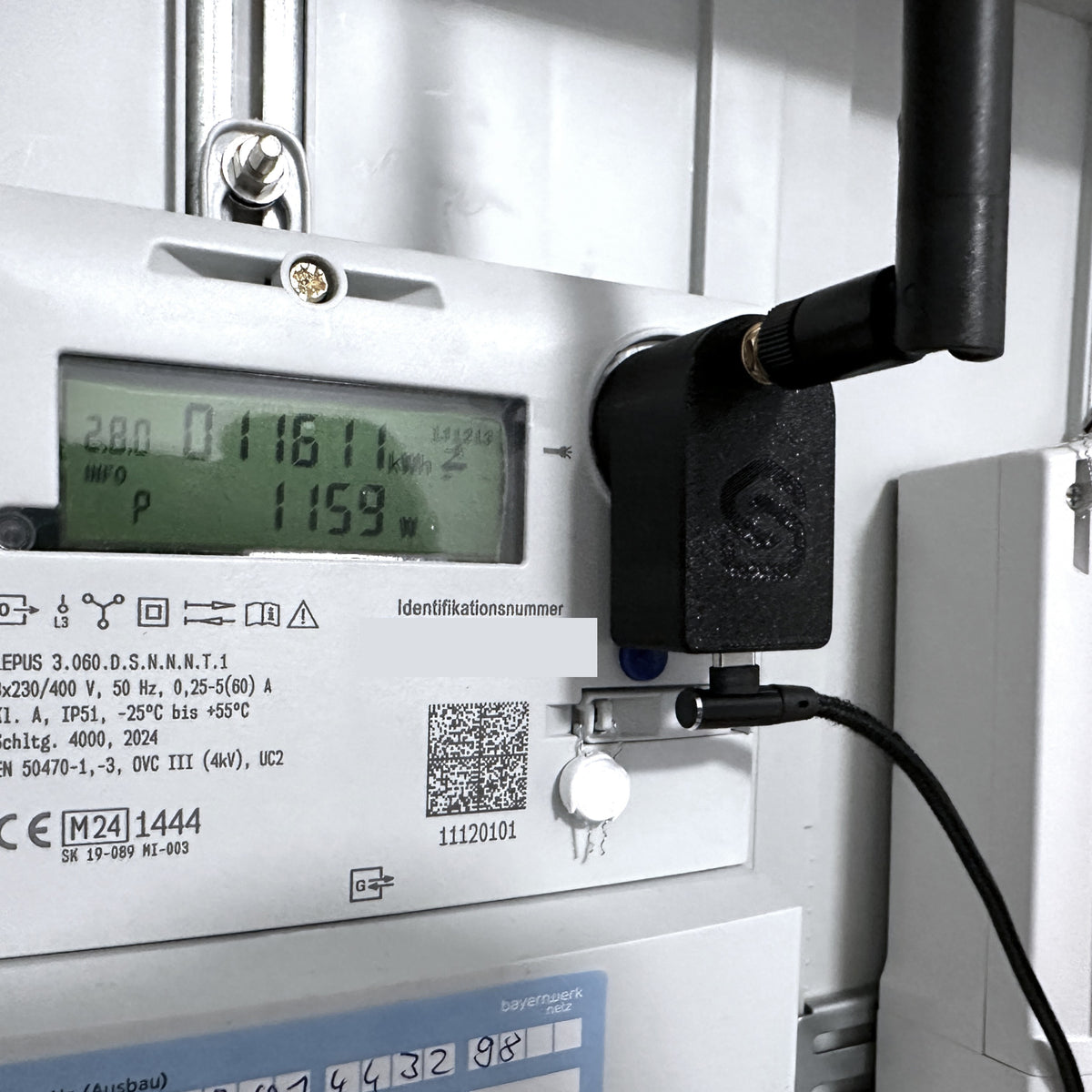 Lesekopf nah am Zähler, Display zeigt 1159 W Momentanleistung, USB-C-Kabel und Antenne seitlich