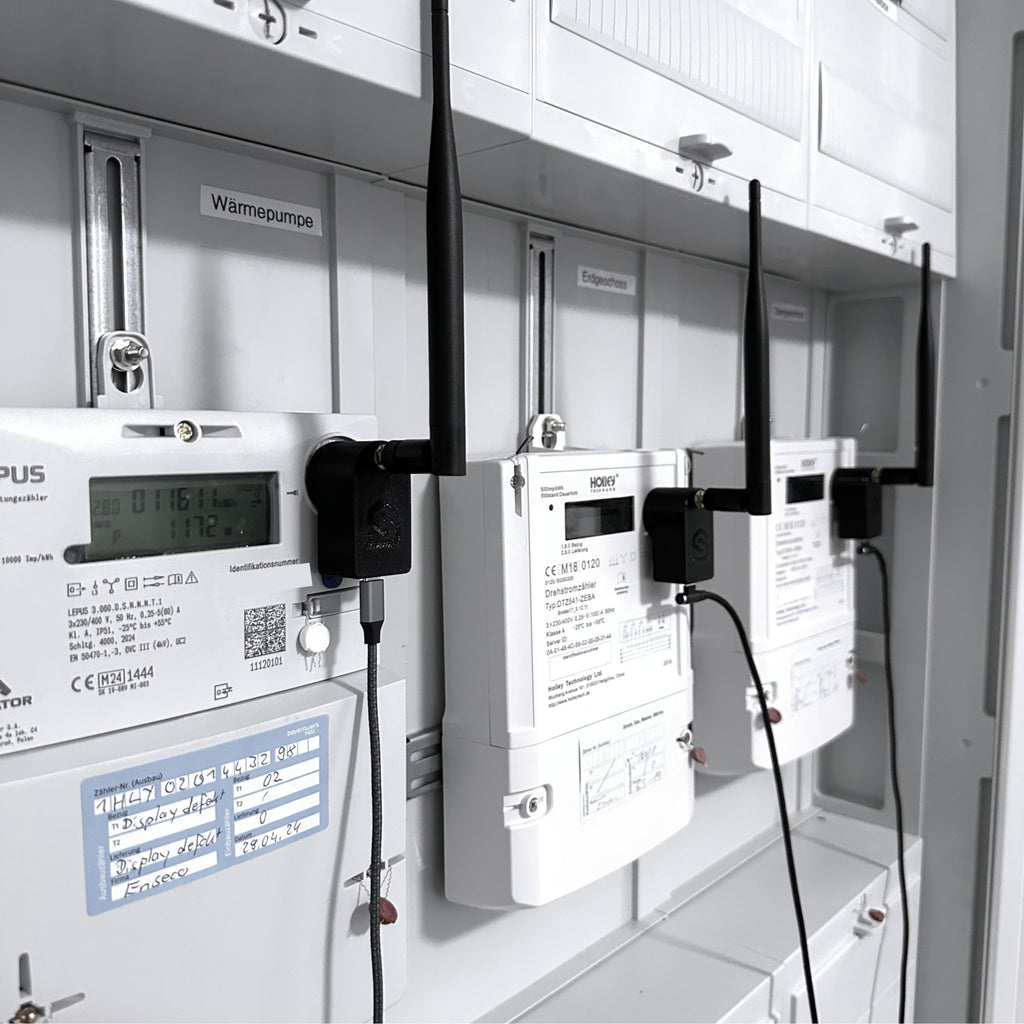 Drei Leseköpfe mit Antennen nebeneinander auf den Zählern für Wärmepumpe und Wohnungen