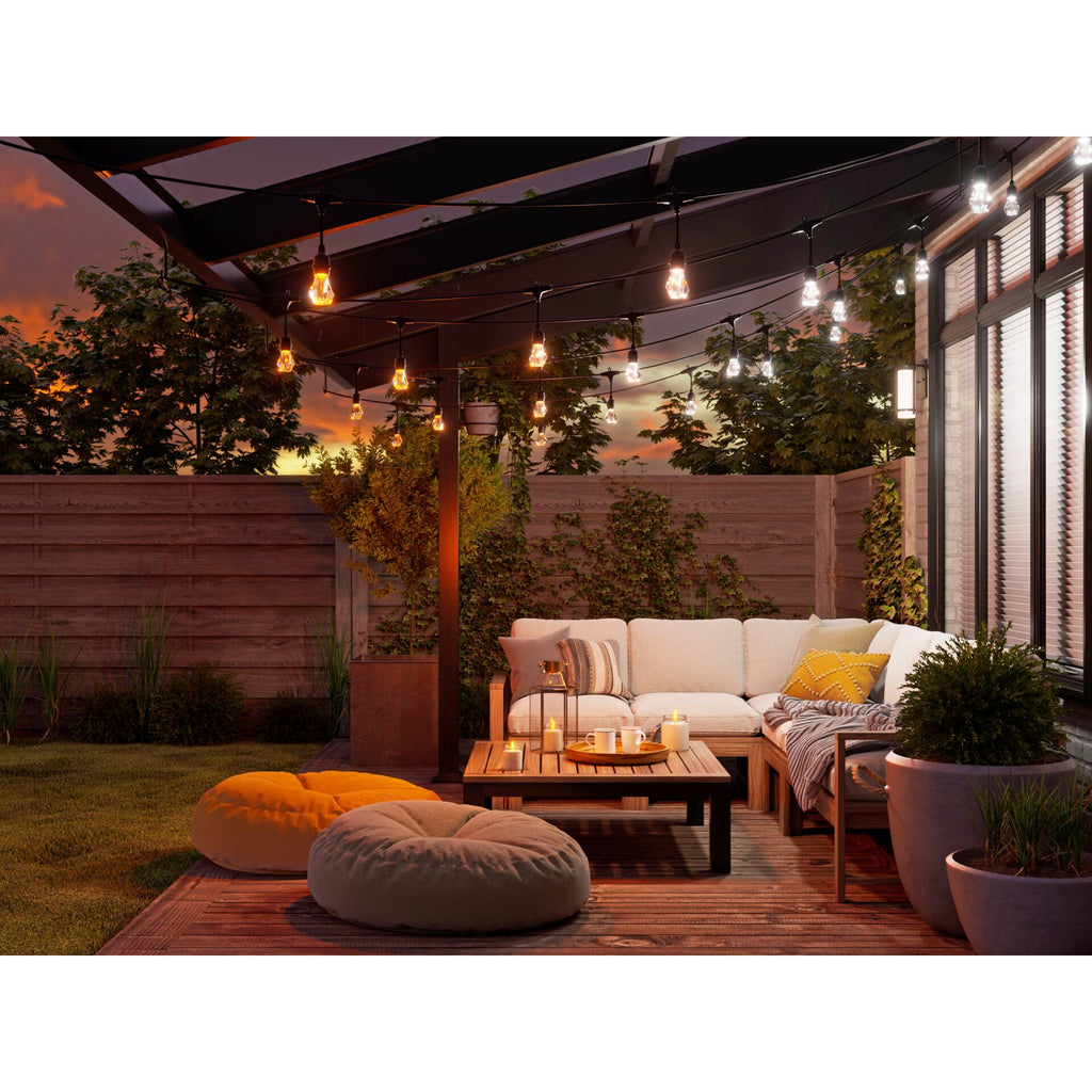 Nanoleaf Outdoor Light String in Warmweiß über Loungesofa und Couchtisch unter einer Pergola