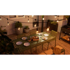 Warmweiß leuchtende Nanoleaf Outdoor Light String über gedecktem Esstisch auf einer Holzterrasse