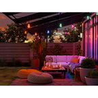 Bunt leuchtendes Nanoleaf Outdoor String Light über Loungesofa und Sitzkissen einer Terrasse am Abend
