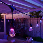 Nahaufnahme einer pink leuchtenden Birne des Nanoleaf Outdoor String Light, weitere Lichter unscharf dahinter