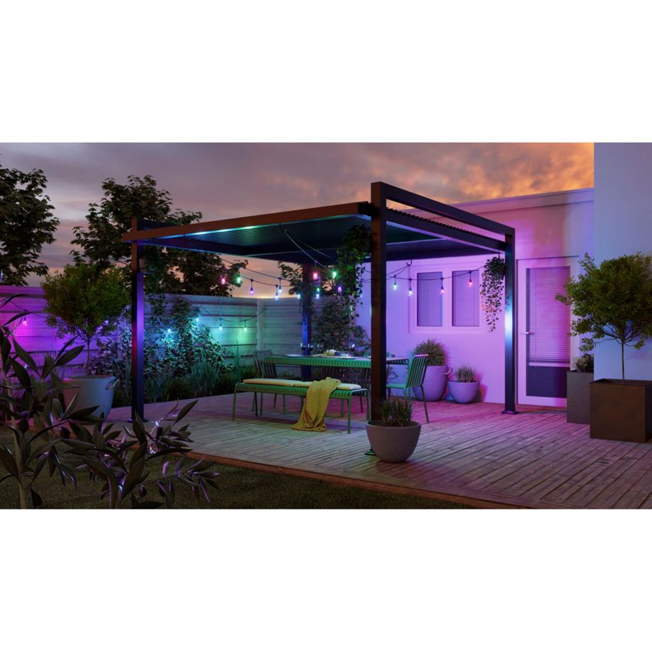 Nanoleaf Outdoor String Light in Grün, Blau und Violett über leerem Essplatz unter der Pergola bei Nacht