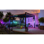 Nanoleaf Outdoor String Light in Grün, Blau und Violett über leerem Essplatz unter der Pergola bei Nacht