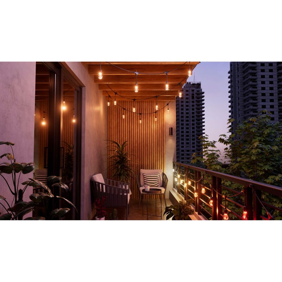 Nanoleaf Outdoor String Light warmweiß auf einem Balkon mit Holzdecke und Sesseln, Hochhäuser im Hintergrund