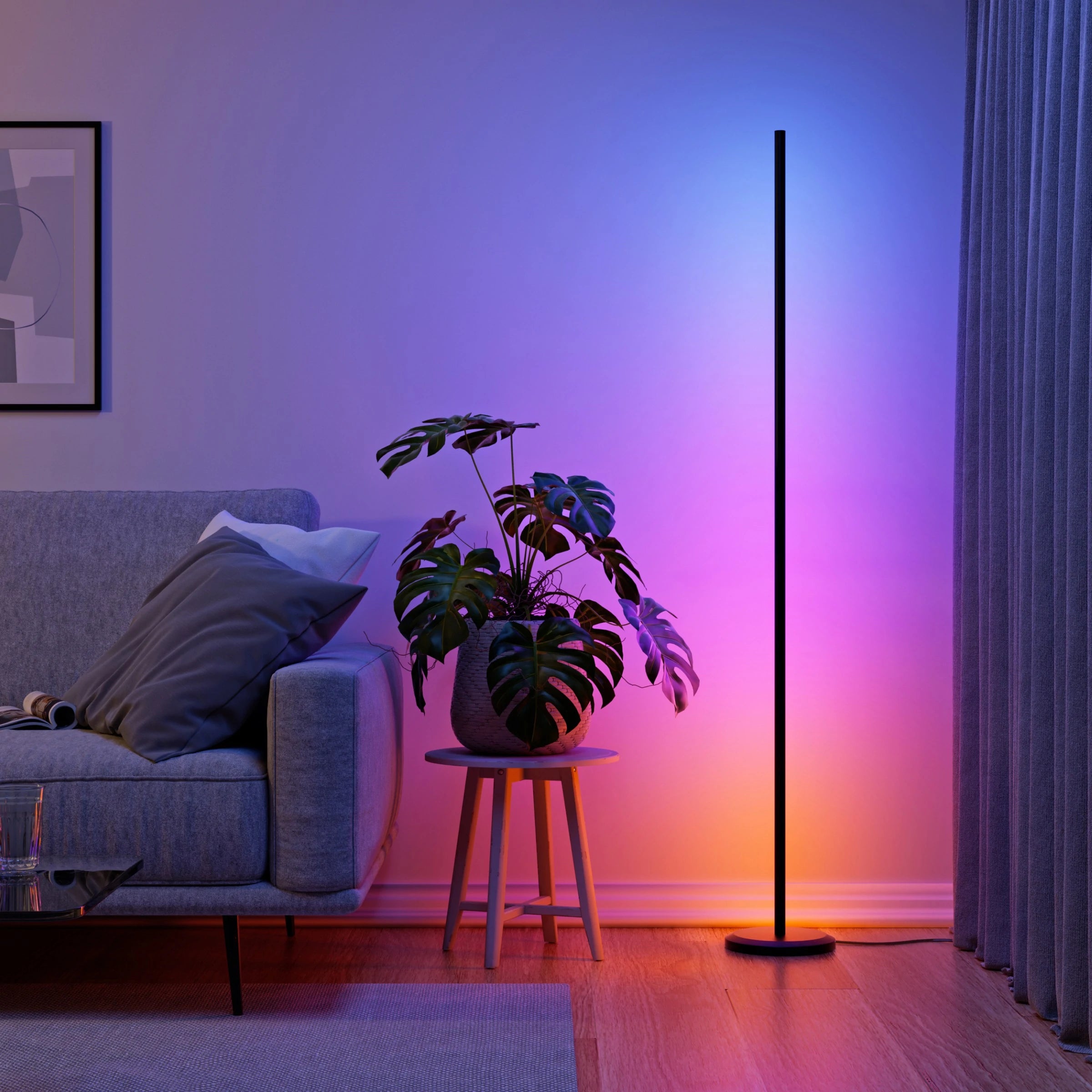 Nanoleaf Floor Lamp mit blau-pinkem Farbverlauf neben Sofa und Monstera im Wohnzimmer