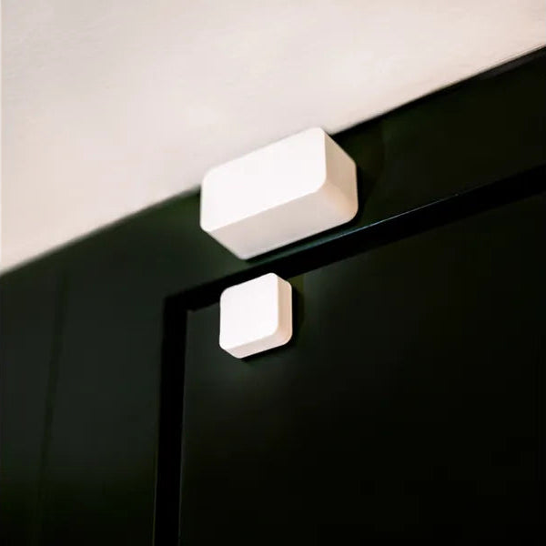Nuki Door Sensor am hellen Türrahmen, der Magnet klebt wenige Zentimeter darunter auf der dunkelgrünen Tür