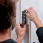 Mann setzt das Nuki Keypad 2 NFC mit beiden Händen an einen weißen Türrahmen