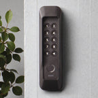Das gesicherte Keypad 2 an einer hellen Wand neben einer Grünpflanze