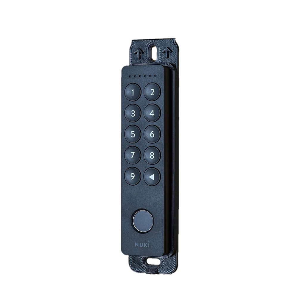 Nuki Keypad 2 auf der Grundplatte des Diebstahlschutzes liegend, Draufsicht mit Pfeilmarkierungen