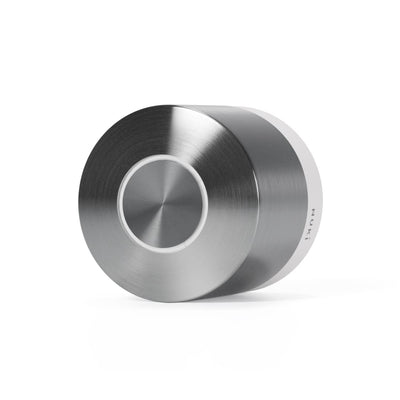 Nuki Smart Lock Ultra liegend, Edelstahlgehäuse mit weißem Basisring, runder Bedientaste und seitlichem NUKI-Schriftzug