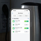 Freedompro App auf dem Smartphone mit vier einzeln geschalteten Steckdosen, dahinter ein Wasserkocher