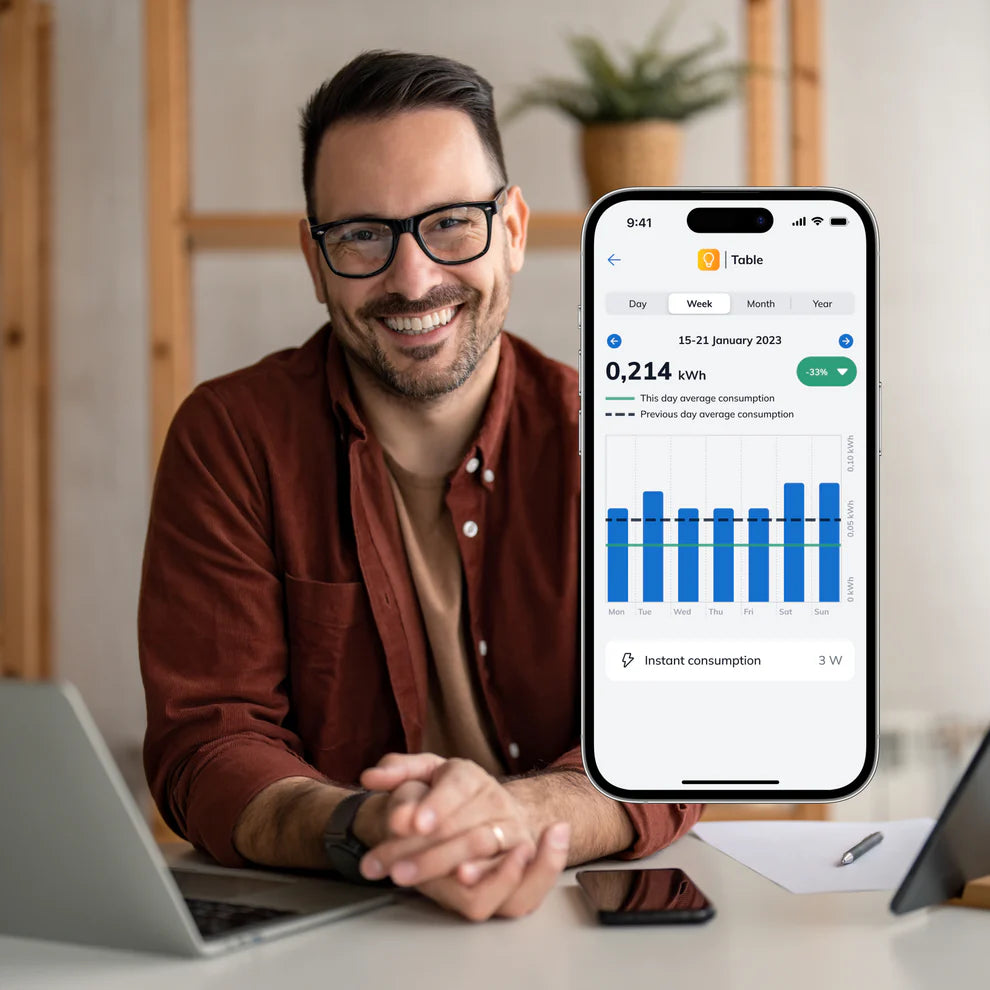 Mann am Schreibtisch, Smartphone zeigt den Wochenstromverbrauch in kWh als Balkendiagramm