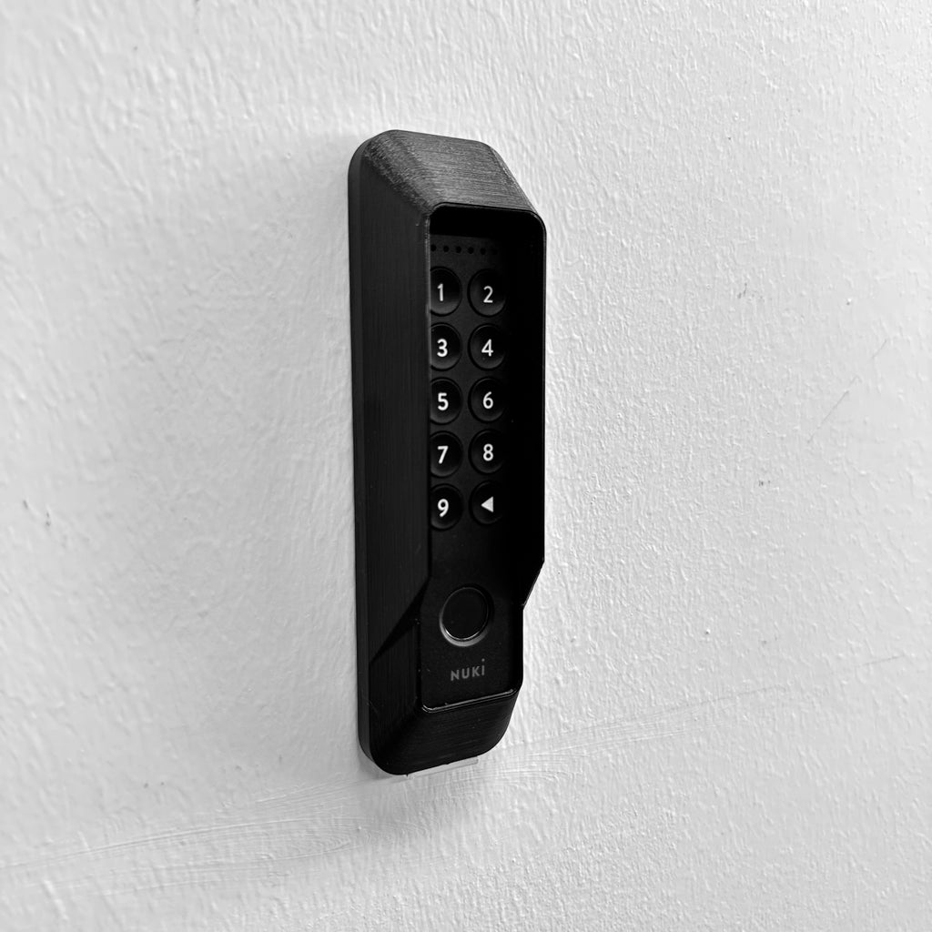 Wandmontiertes Nuki Keypad 2 im Diebstahlschutz von rechts, runde Tasten und Fingerabdrucksensor sichtbar