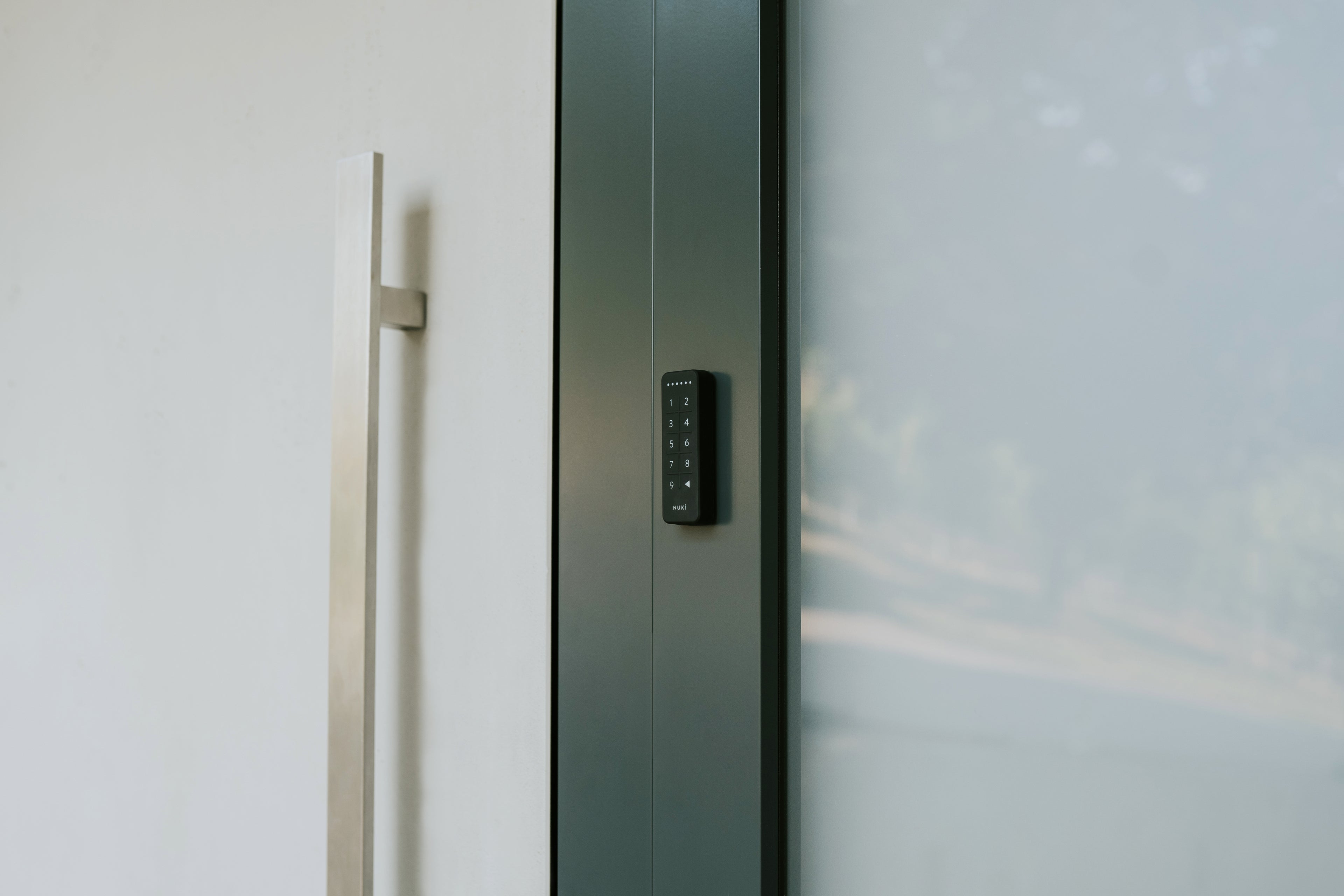 Glastür mit langem Edelstahlgriff und daneben montiertem Nuki Keypad, zeigt die Größenverhältnisse