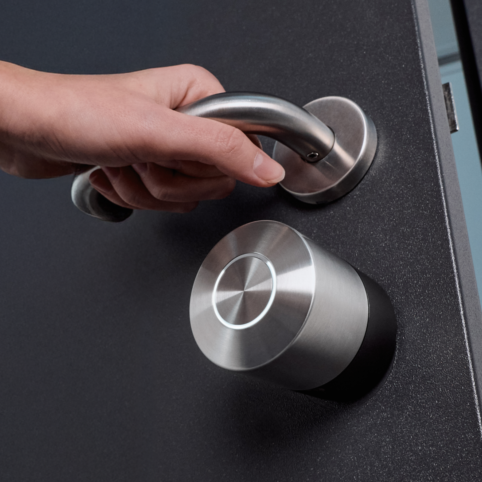 Hand am Türdrücker über dem Nuki Smart Lock Pro, der LED-Ring um die Drucktaste leuchtet weiß