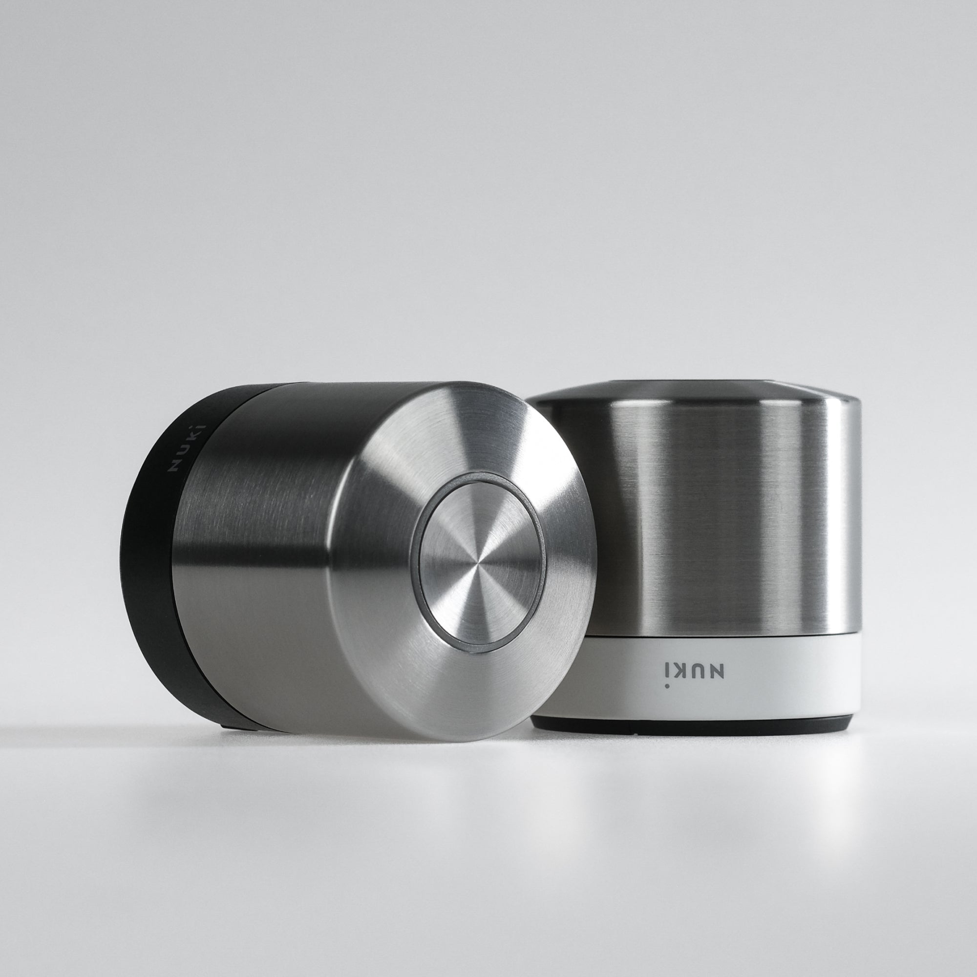 Zwei Nuki Smart Lock Ultra nebeneinander, eines mit schwarzem, eines mit weißem Basisring