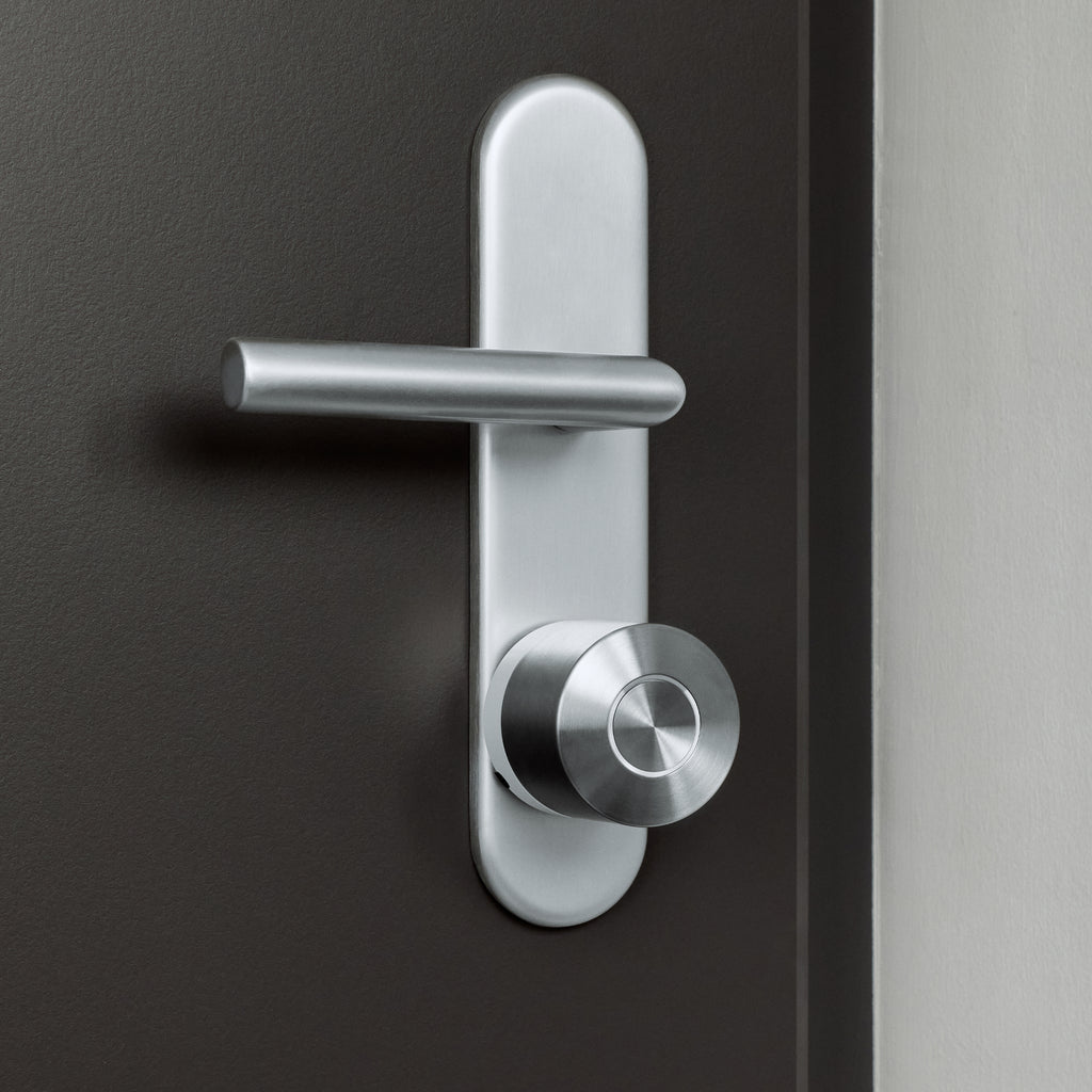 Dunkelbraune Wohnungstür mit Langschild und Drücker, darunter das montierte Nuki Smart Lock Ultra