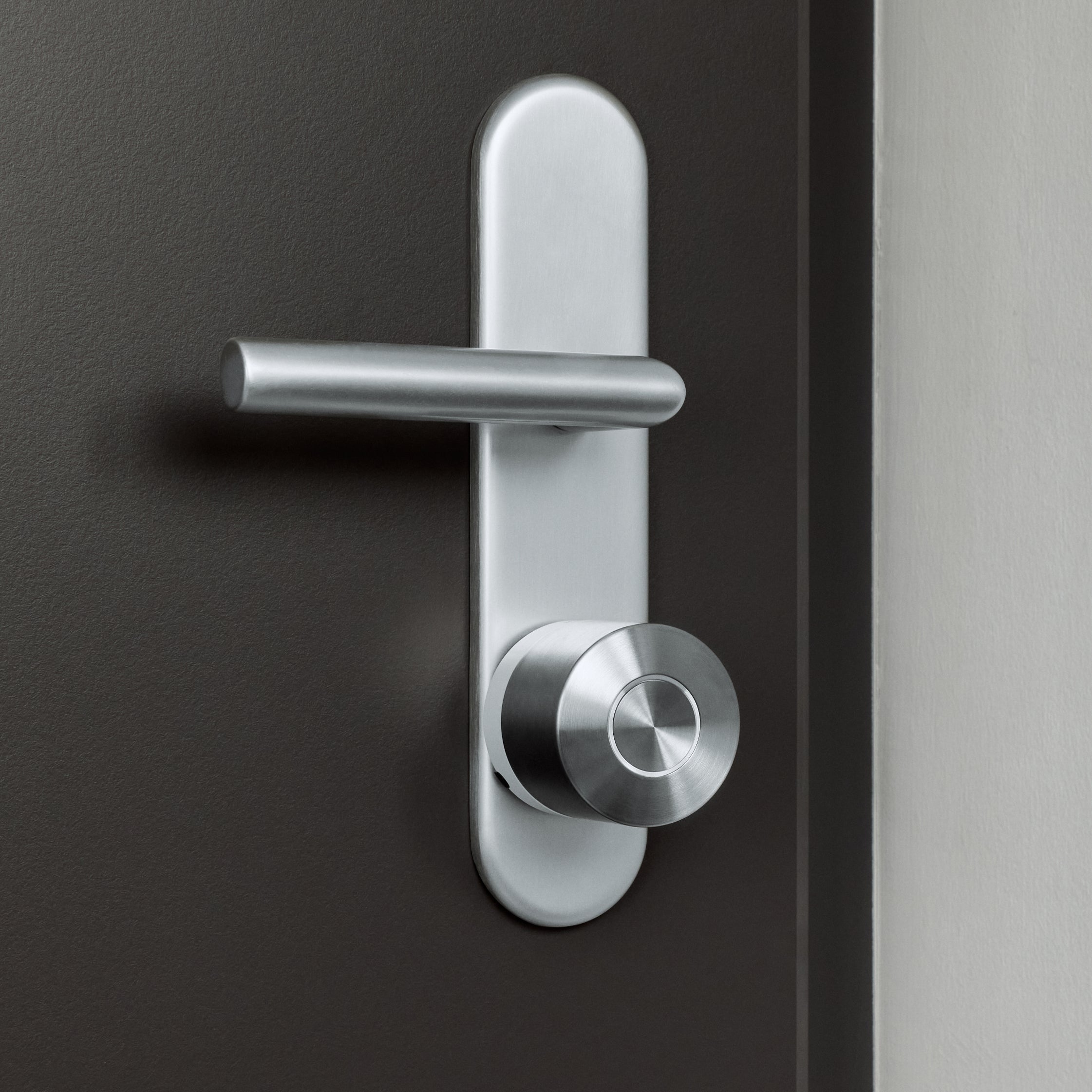Dunkelbraune Wohnungstür mit Langschild und Drücker, darunter das montierte Nuki Smart Lock Ultra
