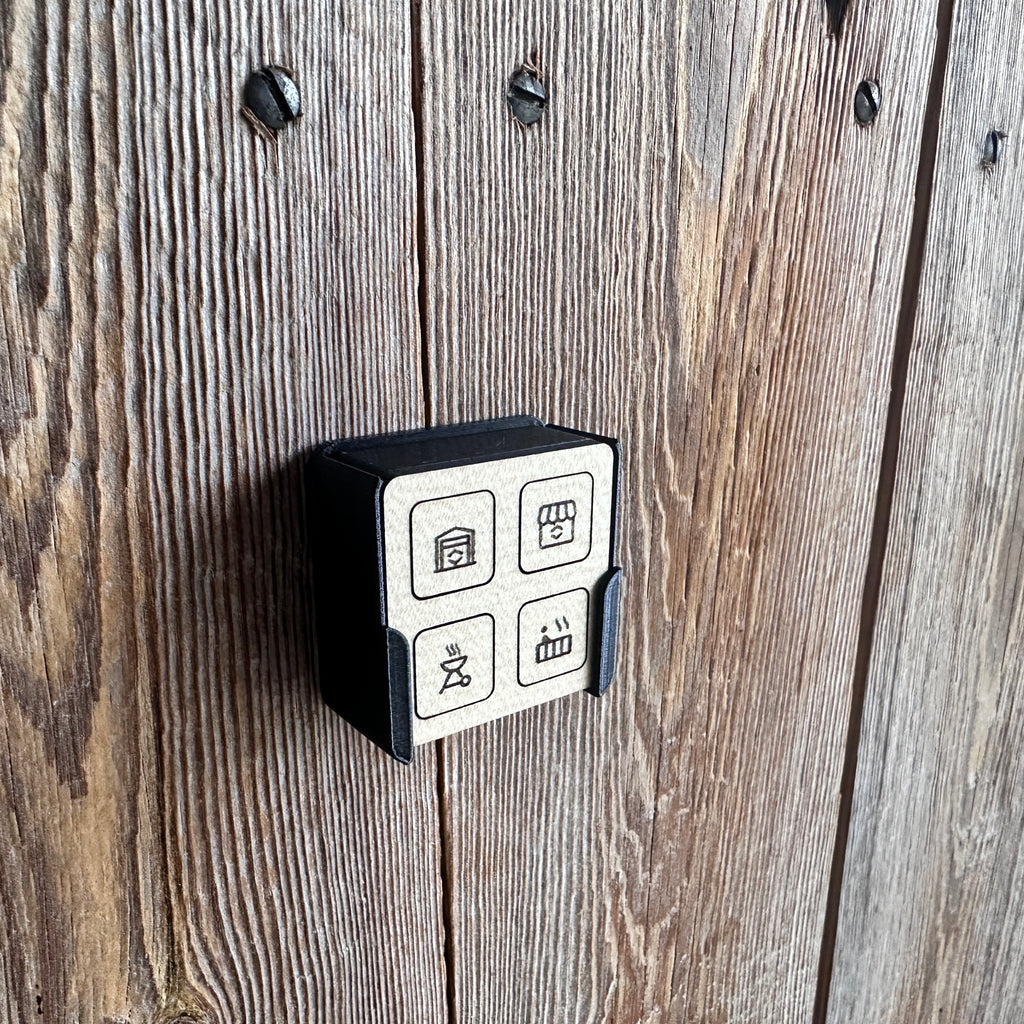 Fernbedienung mit weißen Tastflächen und Symbolen an einer Altholzwand