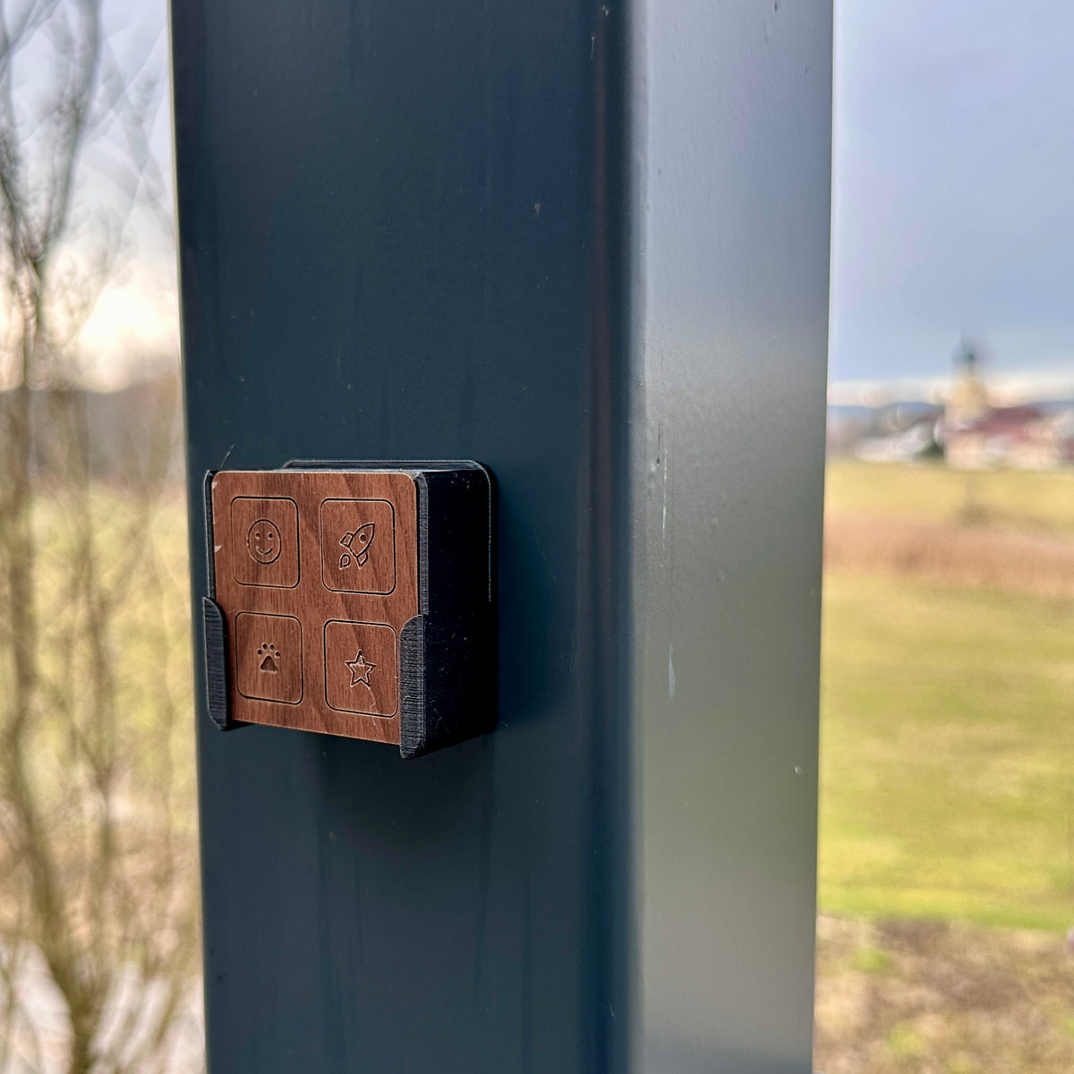 Fernbedienung in Nussbaum in ihrer Wandhalterung an einem dunklen Pfosten