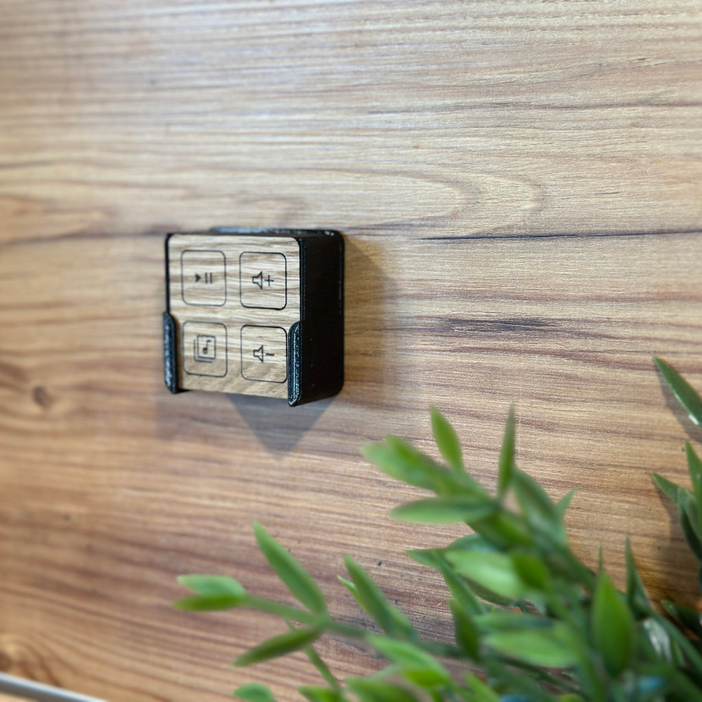 Fernbedienung mit hellen Tastflächen in der Wandhalterung an einer Holzwand